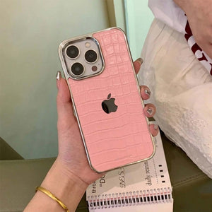Person holding a pink crocodile-patterned phone case with an Apple logo.