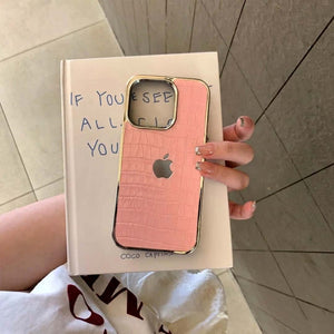 Pink phone case with gold accents held over a book titled 'If You See All of Me'.