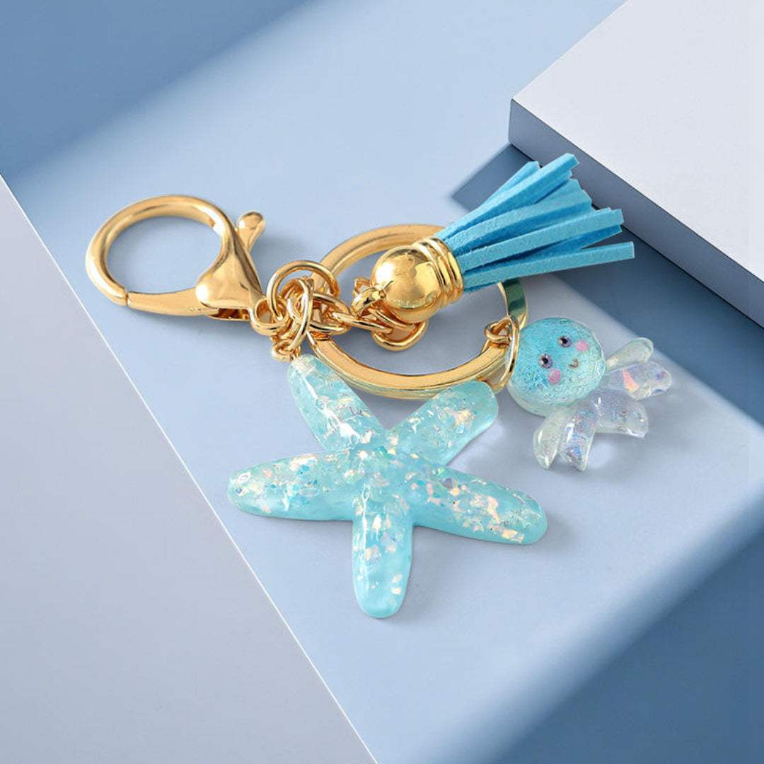 Keychain with starfish charm, tassel, and gold clasp on a light blue background