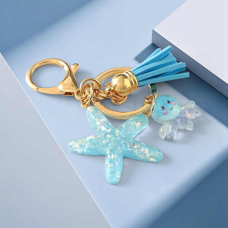 Keychain with starfish charm, tassel, and gold clasp on a light blue background