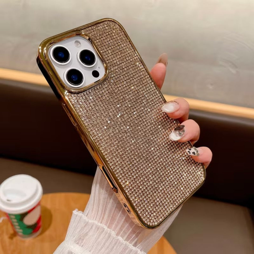 Hand holding a rose gold phone case with rhinestone details, blurred background